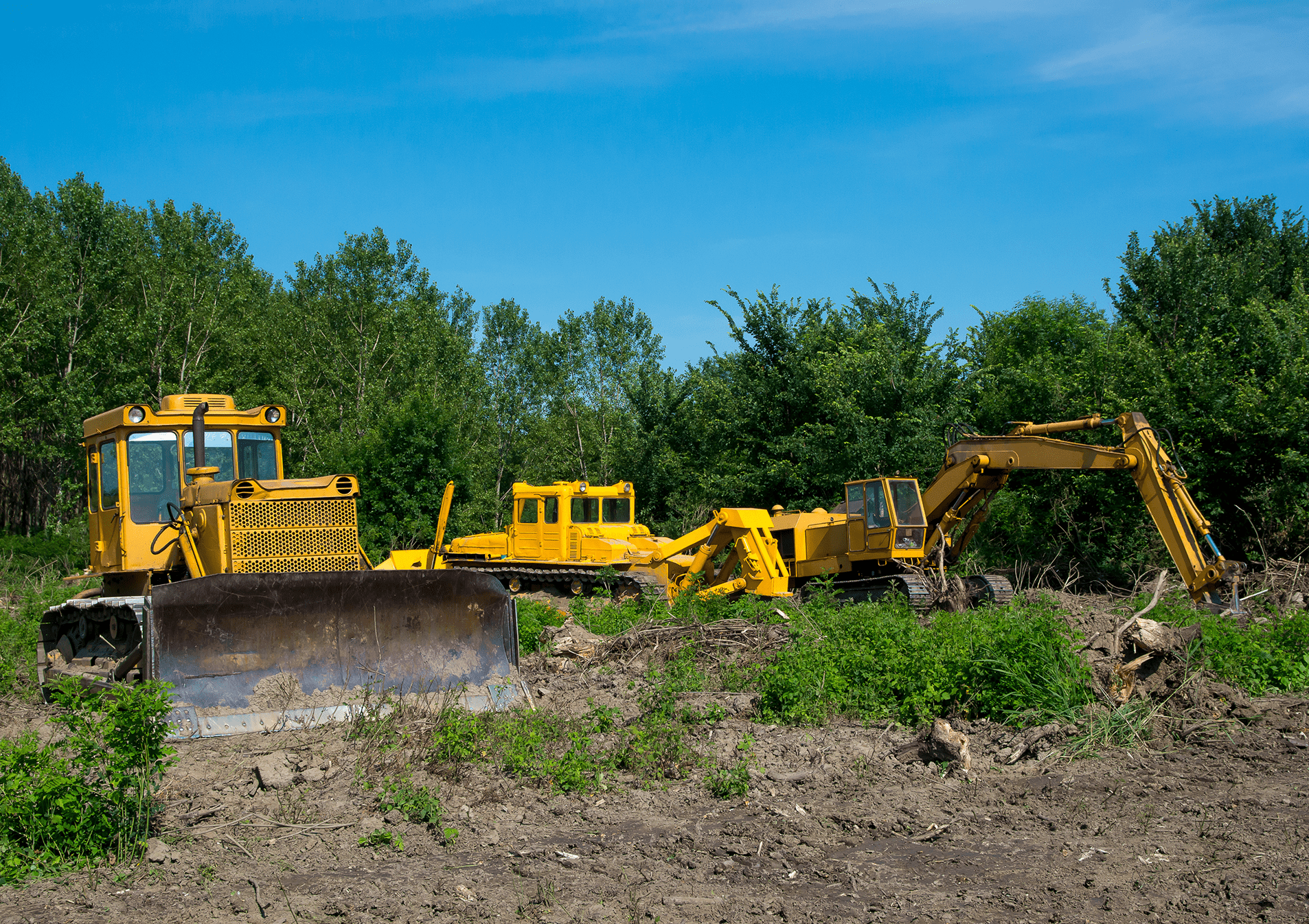 Yellow construction vehicles on a dirt site.